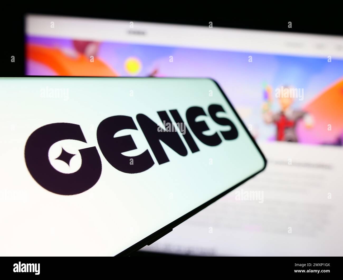 Téléphone portable avec le logo de la société américaine de technologie d'avatar Genies Inc en face du site Web de l'entreprise. Focus à gauche de l'écran du téléphone. Banque D'Images