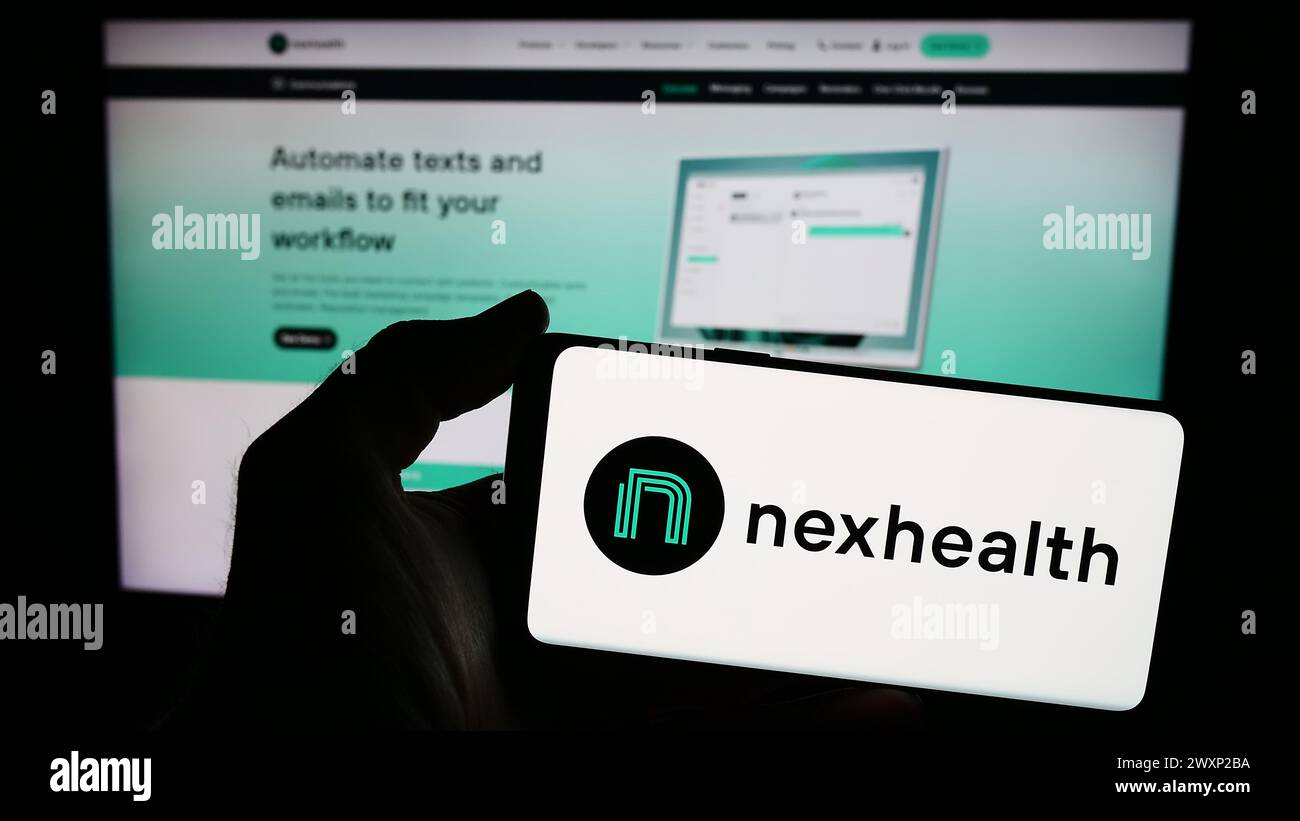 Personne tenant un smartphone avec le logo de la société américaine de logiciels de soins de santé NexHealth Inc en face du site Web. Concentrez-vous sur l'affichage du téléphone. Banque D'Images