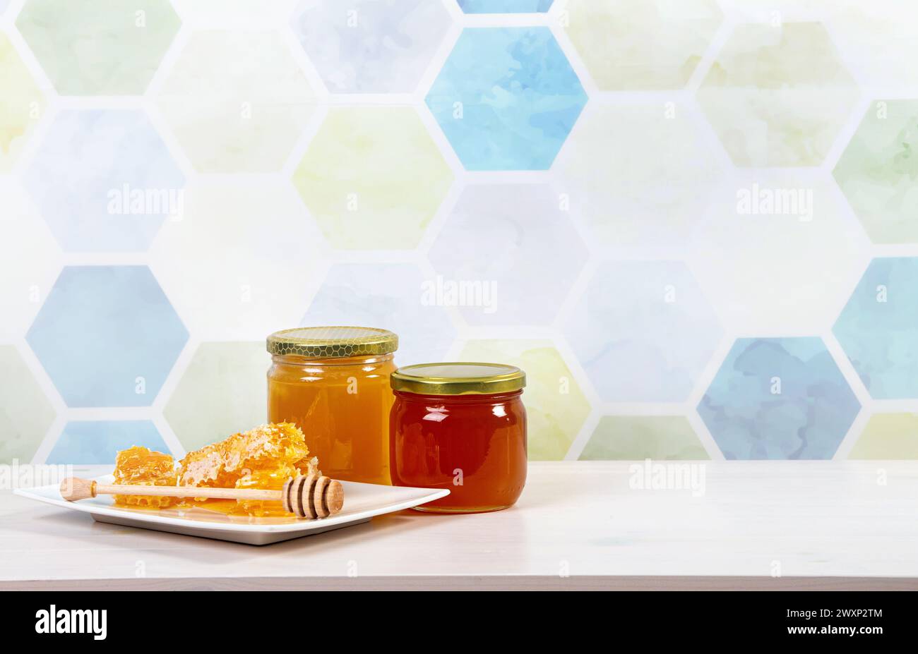 Bocaux de miel en verre avec du miel de couleur différente à l'intérieur, beaucoup d'espace de copie sur fond de motif nid d'abeille bleu clair. Concept de fond de frontière de miel. Banque D'Images