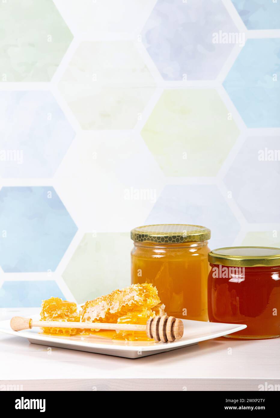 Bocaux de miel en verre avec du miel de couleur différente à l'intérieur, beaucoup d'espace de copie sur fond de motif nid d'abeille bleu clair. Concept de fond de frontière de miel. Banque D'Images