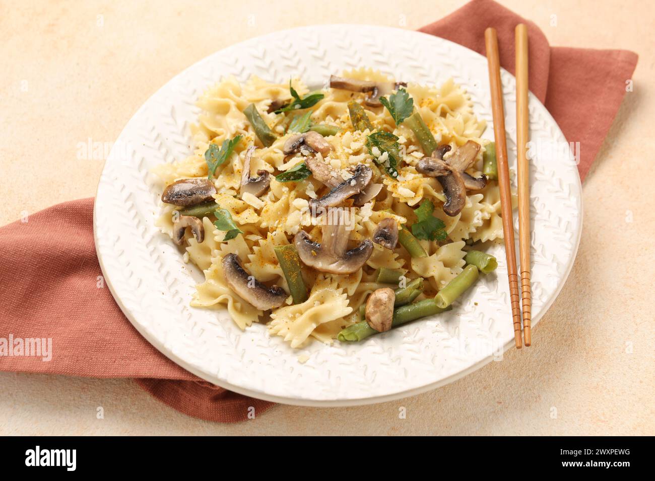 Pâtes végétariennes avec champignons, persil, haricots et fromage sur table texturée orange Banque D'Images