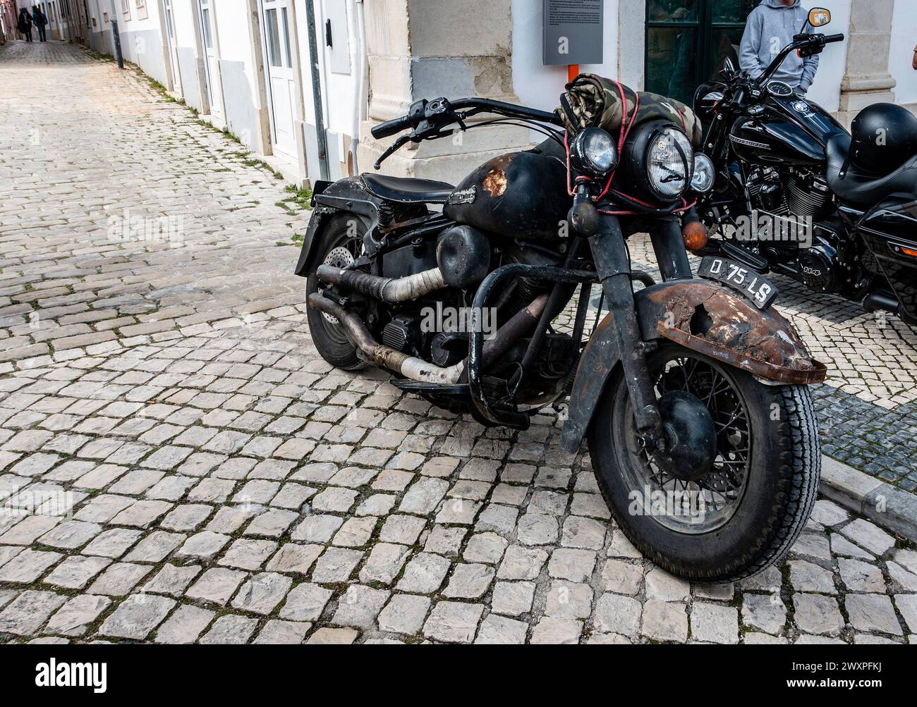 Une moto vintage rouillée avec patine distincte se trouve stationnée sur une vieille rue pavée, à Loule, au Portugal. Banque D'Images