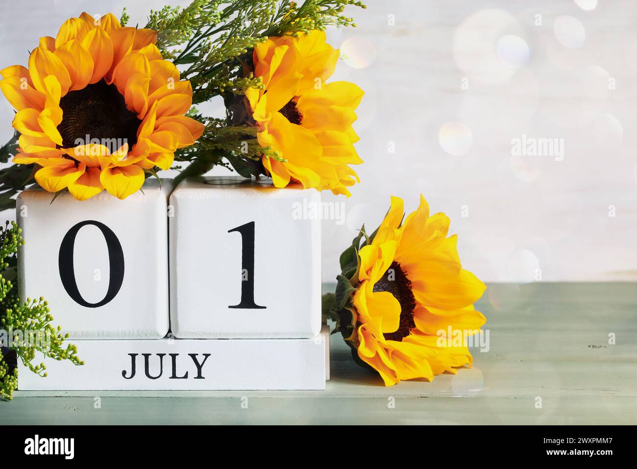 Blocs de calendrier en bois blanc avec la date du 1er juillet et beau bouquet de tournesol avec bokeh. Mise au point sélective avec arrière-plan flou. Banque D'Images