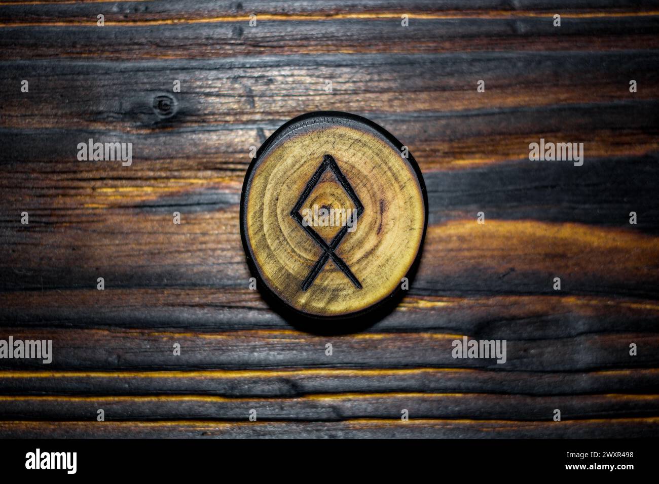 Rune Odal (Othala) sculptée dans du bois sur un fond en bois - Elder Futhark Banque D'Images