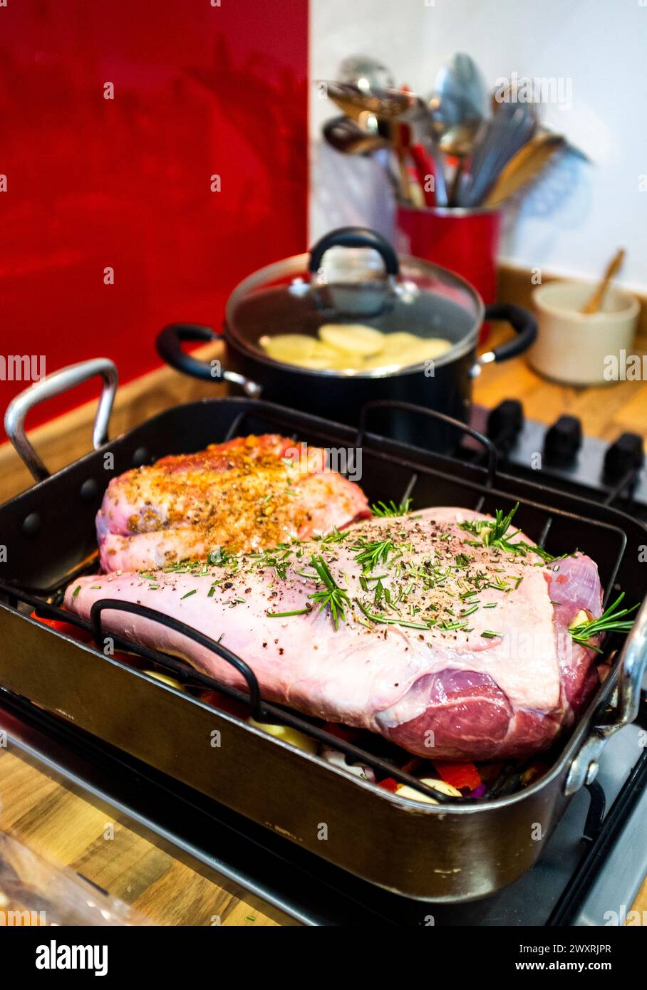 Préparer une cuisse et une petite épaule d'agneau pour rôtir avec de l'ail et des herbes de romarin Banque D'Images