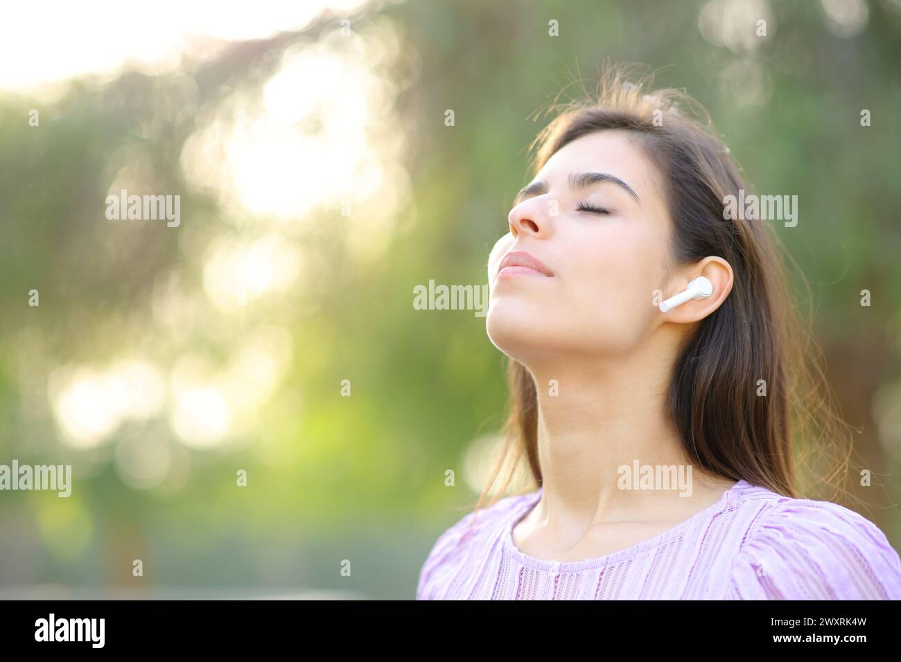 Femme respirant et méditant avec un écouteur dans un parc Banque D'Images