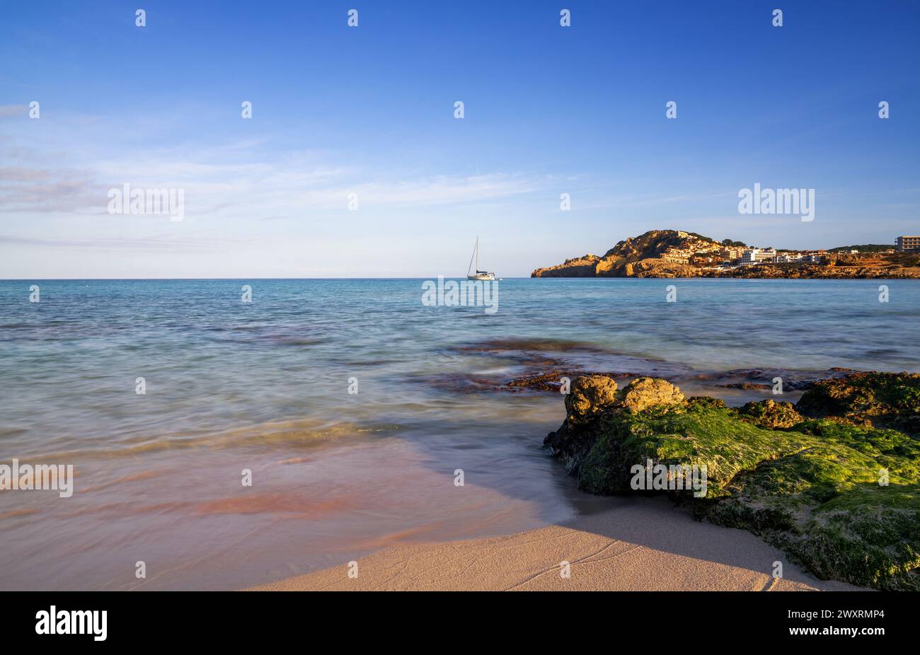 Une vue sur la baie idyllique et la plage de Cala Agulla dans l'est de Majorque avec un voilier au premier plan Banque D'Images