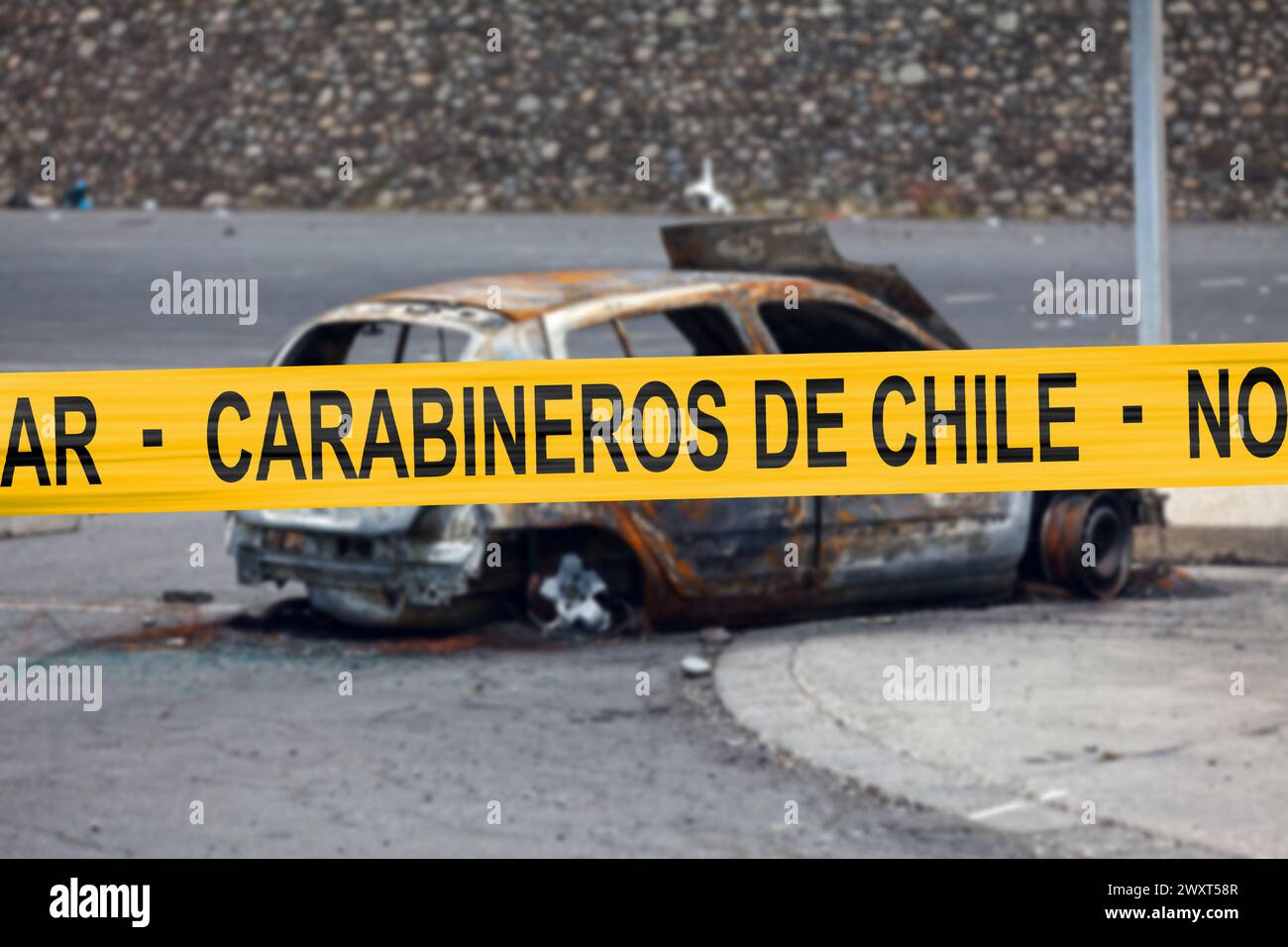 Voiture brûlée par un pyromane avec une bande de police avec écrit en espagnol 'carabineros de Chile - No pasar'. Banque D'Images