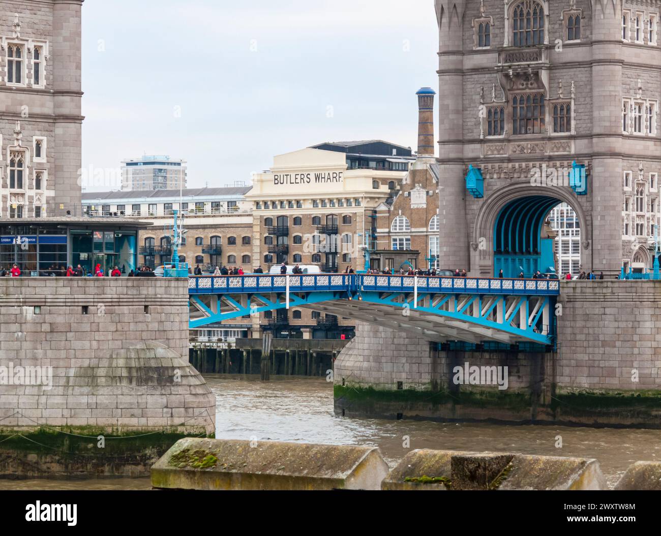 Le bâtiment Butlers Wharf, classé Grade II, sur la rive sud de la Tamise, est vu à travers les tours de l'emblématique London Bridge, Londres, Royaume-Uni Banque D'Images