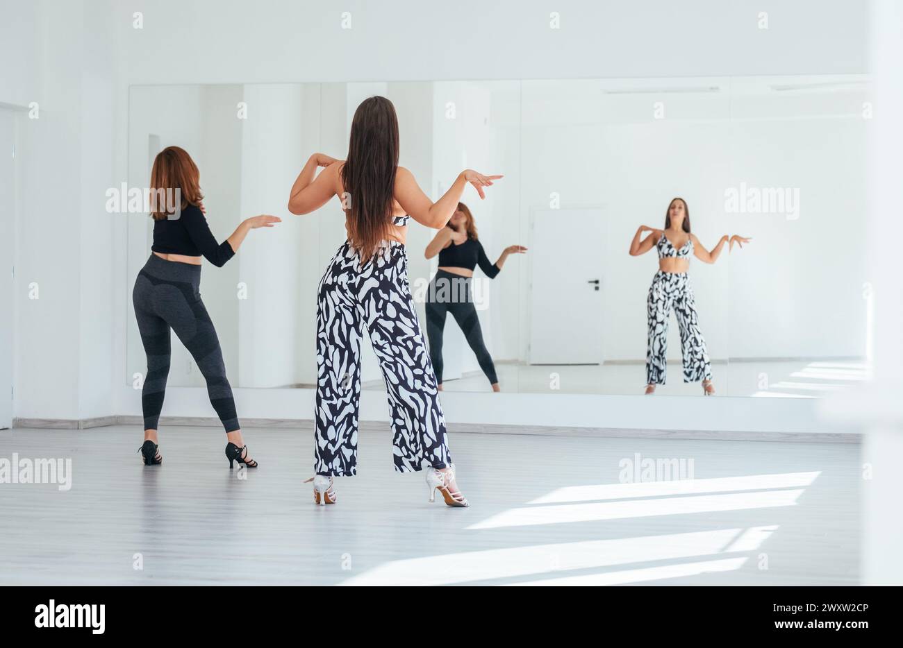 Groupe de femmes dansantes gracieuses faisant des mouvements de danse élégants dans la salle spacieuse de couleur blanche avec grand mur de miroir.expressions des gens pendant la danse, beau Banque D'Images