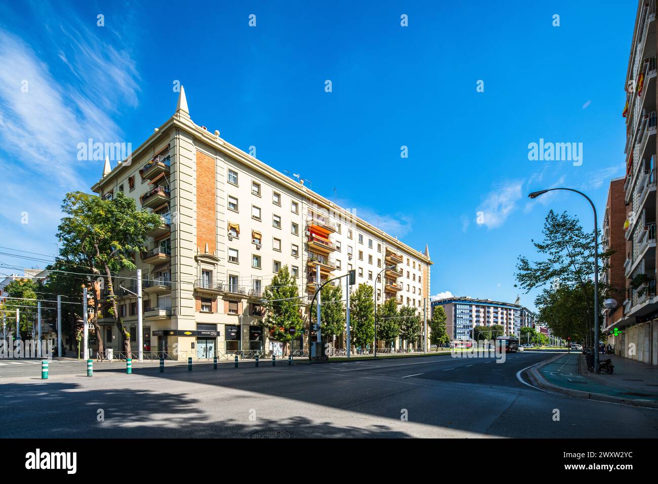 Immeuble résidentiel baigné de soleil au Prado de San Sebastian, avec piétons et verdure. Banque D'Images