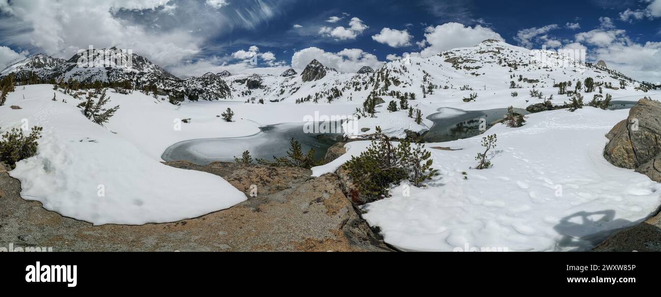 Pacific Crest Trail. Une vue panoramique sur une chaîne de montagnes enneigée avec un lac au premier plan. Le ciel est clair et bleu, et le landsca enneigé Banque D'Images
