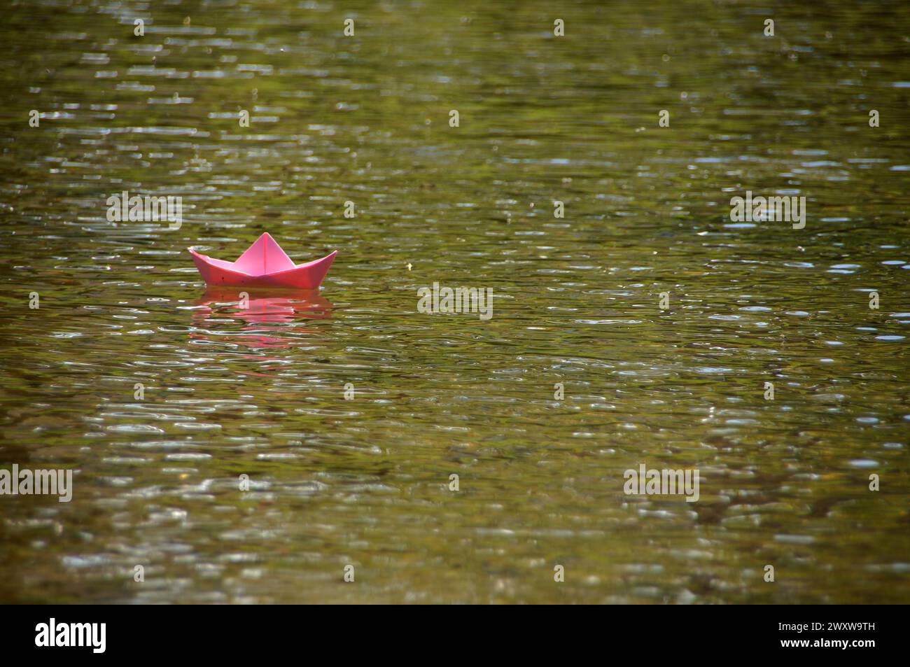 Bateau en papier rose flottant sur la rivière Banque D'Images