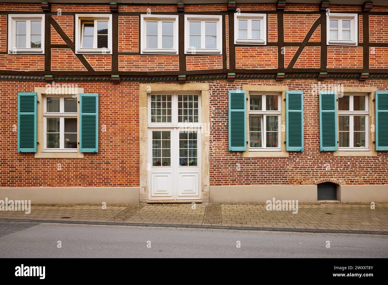 Façade d'une maison en briques à colombages avec des fenêtres blanches, une puissante porte d'entrée et des volets bleu-vert à Warendorf, quartier Warendorf, Nord Banque D'Images