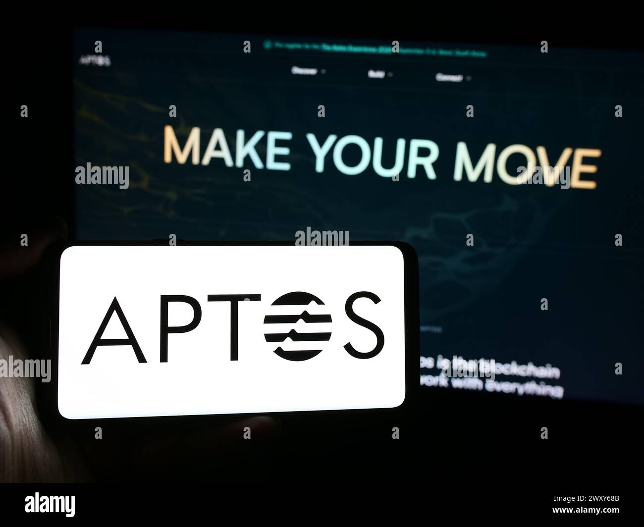 Personne tenant un smartphone avec le logo de l'organisation de développement de protocole Aptos Foundation devant le site Web. Concentrez-vous sur l'affichage du téléphone. Banque D'Images