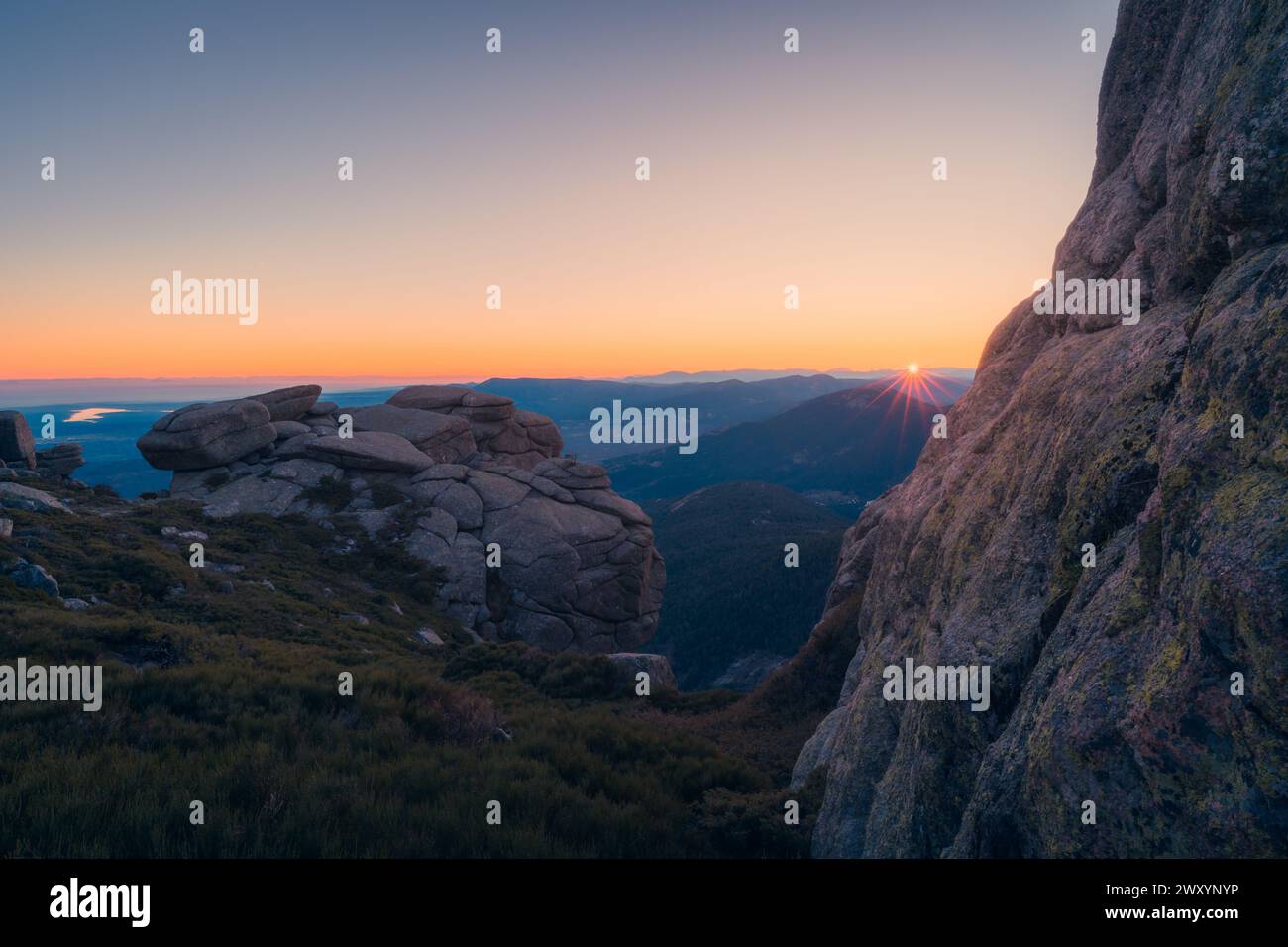 Un coucher de soleil serein à Siete Picos, Sierra de Guadarrama, avec des formations rocheuses et des rafales de soleil Banque D'Images