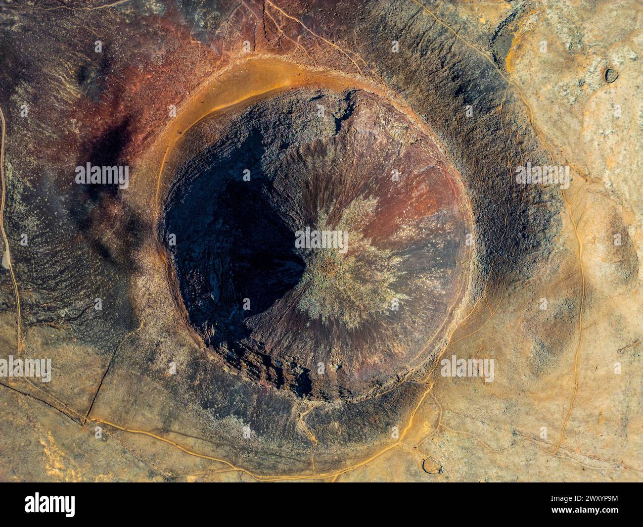 Une prise de vue aérienne capture l'étendue époustouflante d'un cratère volcanique, présentant un éventail de textures et de couleurs allant des riches rouilles aux nuances profondes de Br Banque D'Images