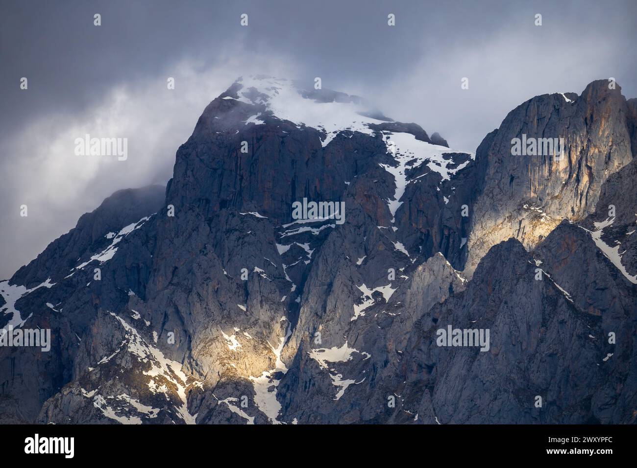 Les sommets ensoleillés surplombent le terrain accidenté du parc national des Picos de Europa, drapé dans la neige et entouré de nuages. Banque D'Images