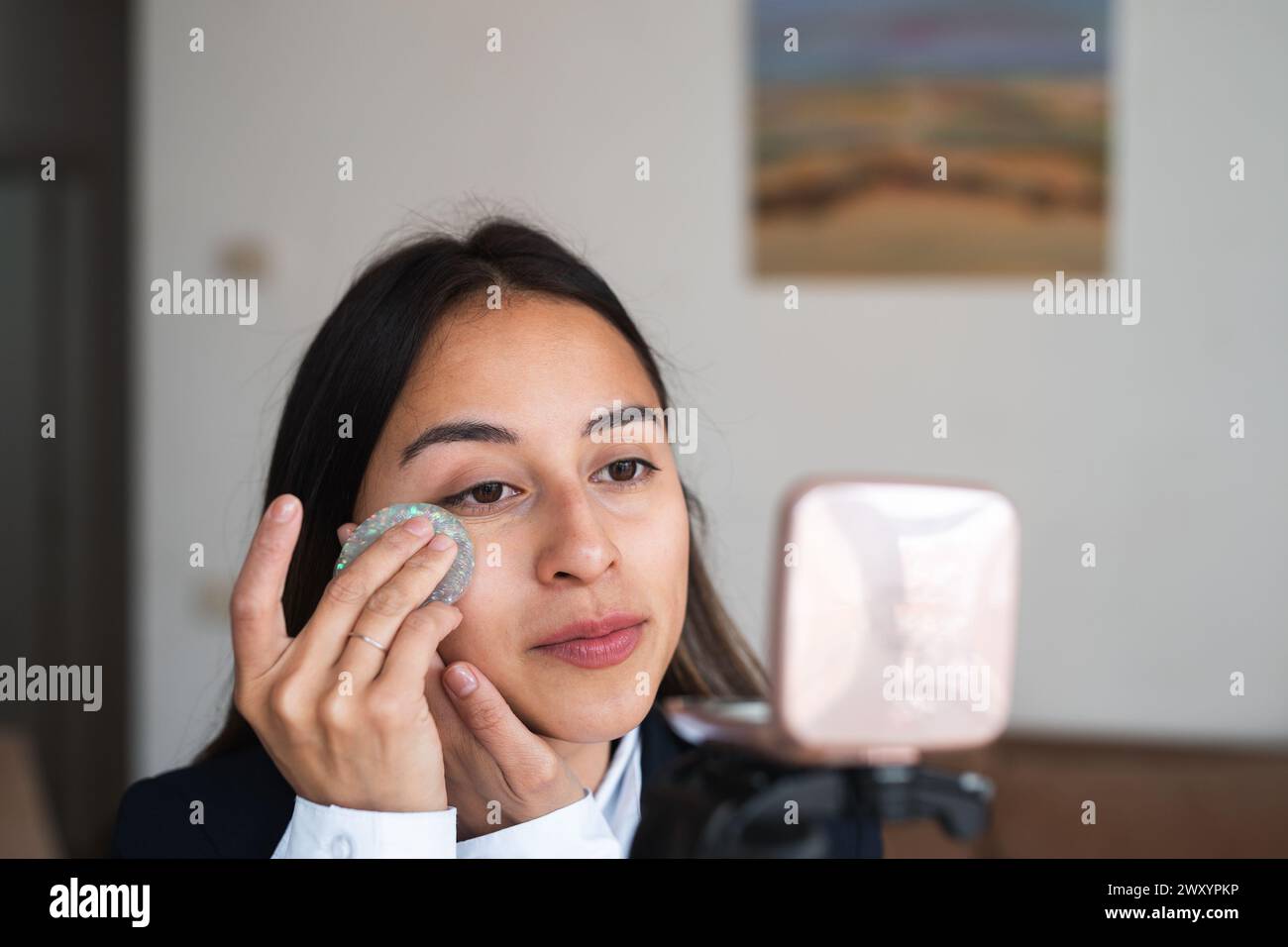 Une jeune femme utilise un tampon démaquillant réutilisable sur son visage, enregistrant un tutoriel Banque D'Images