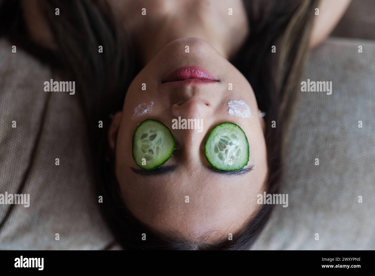 Une image descendante capturant une personne sereine avec des tranches de concombre sur les yeux, indiquant une journée de spa ou une routine de soins de la peau Banque D'Images