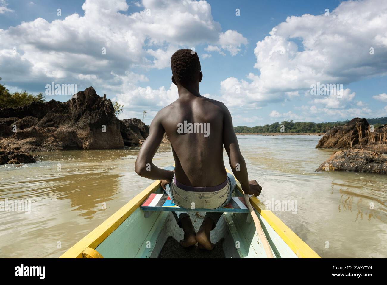 Pirogue, canot de dugout sur la rivière Maroni, Guyane française : homme vu de derrière à l'avant de la pirogue. Ici, sonder la profondeur de la rivière Wit Banque D'Images