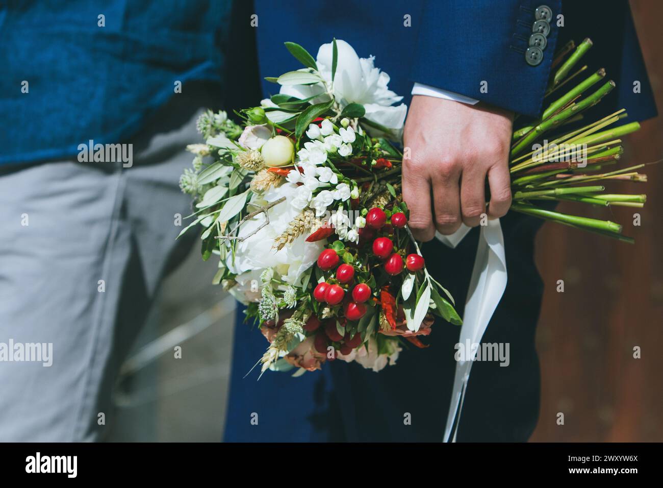 main du marié saisissant fermement un bouquet de mariage élégant et diversifié. Incarne l'engagement et le soin Banque D'Images