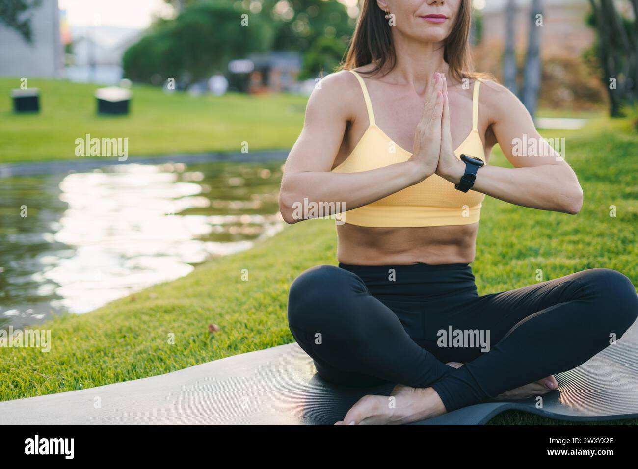 Femme adulte Happy positive fit pratiquant le yoga à l'air frais ouvert à l'extérieur assis pieds nus sur un tapis de yoga noir. La méditation a de bons bienfaits pour la santé Banque D'Images