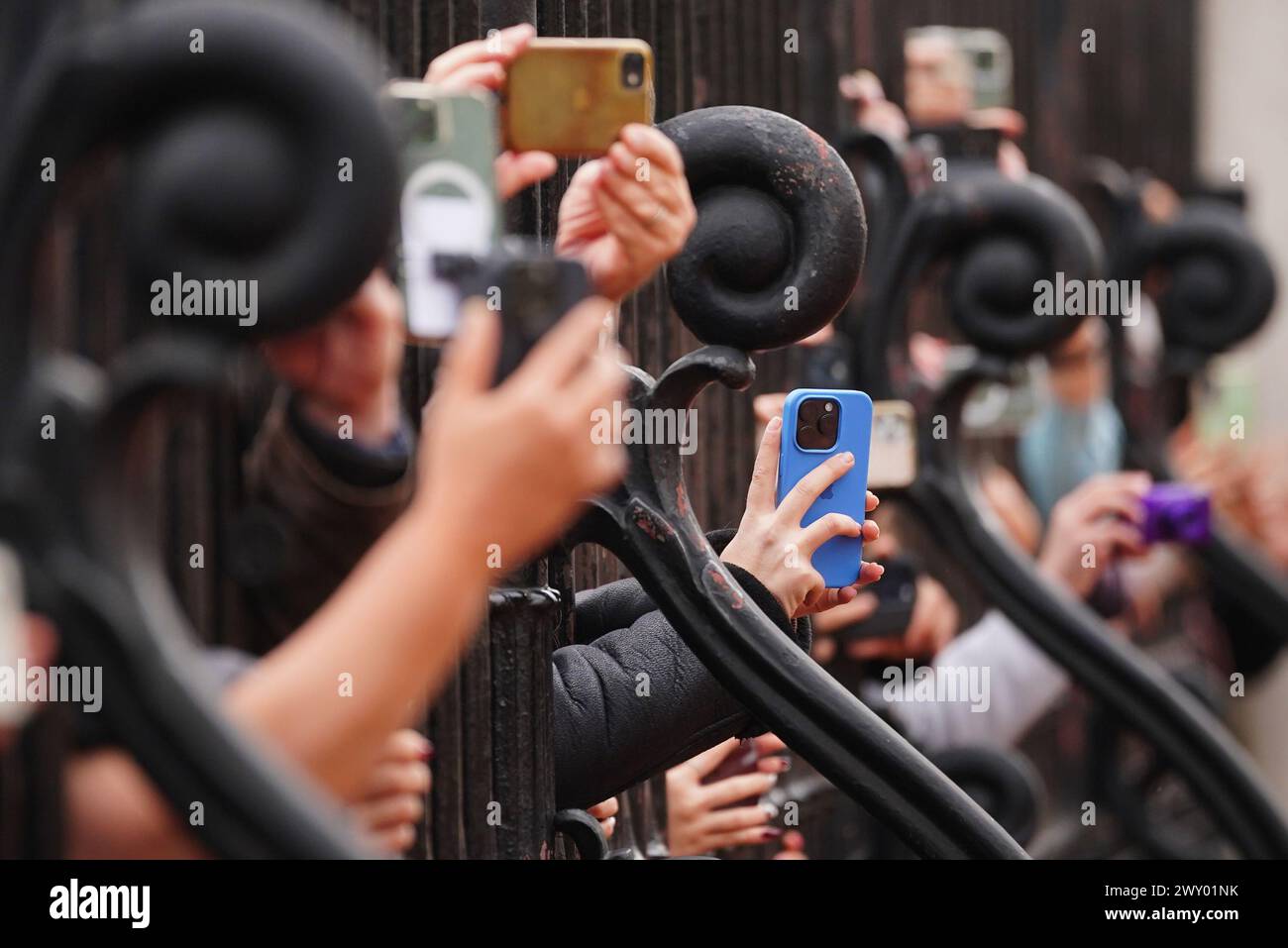 Les membres du public utilisent leur téléphone pour filmer et photographier la bande des gardes gallois lors de la cérémonie de relève de la garde au Palais de Buckingham, à Londres, alors qu'ils interprètent l'hymne de l'OTAN pour célébrer le 75e anniversaire de l'Organisation du Traité de l'Atlantique Nord. Date de la photo : mercredi 3 avril 2024. Banque D'Images