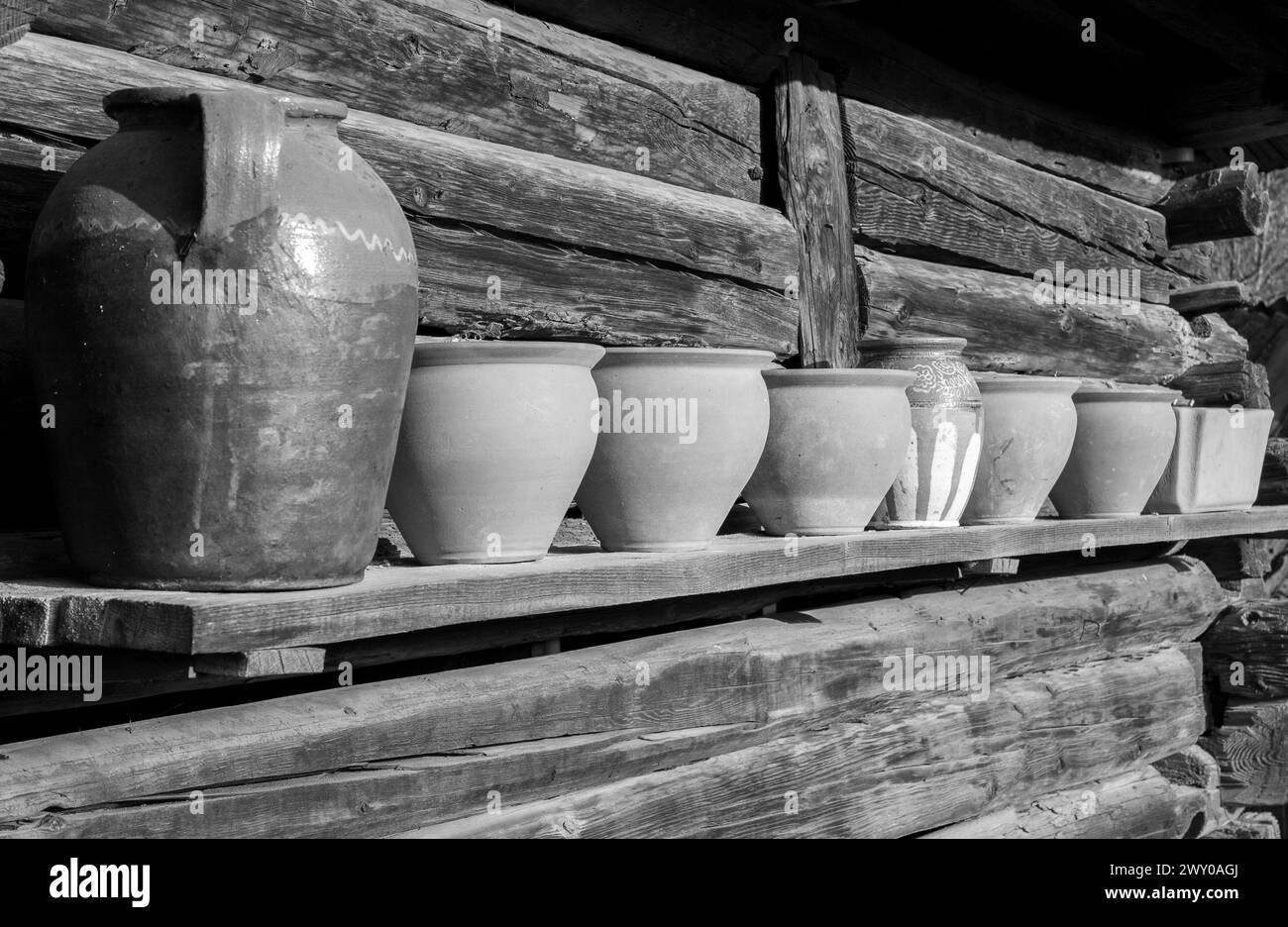 Quelques vieux pots en argile sur une étagère en bois avec une mise au point sélective en noir et blanc Banque D'Images