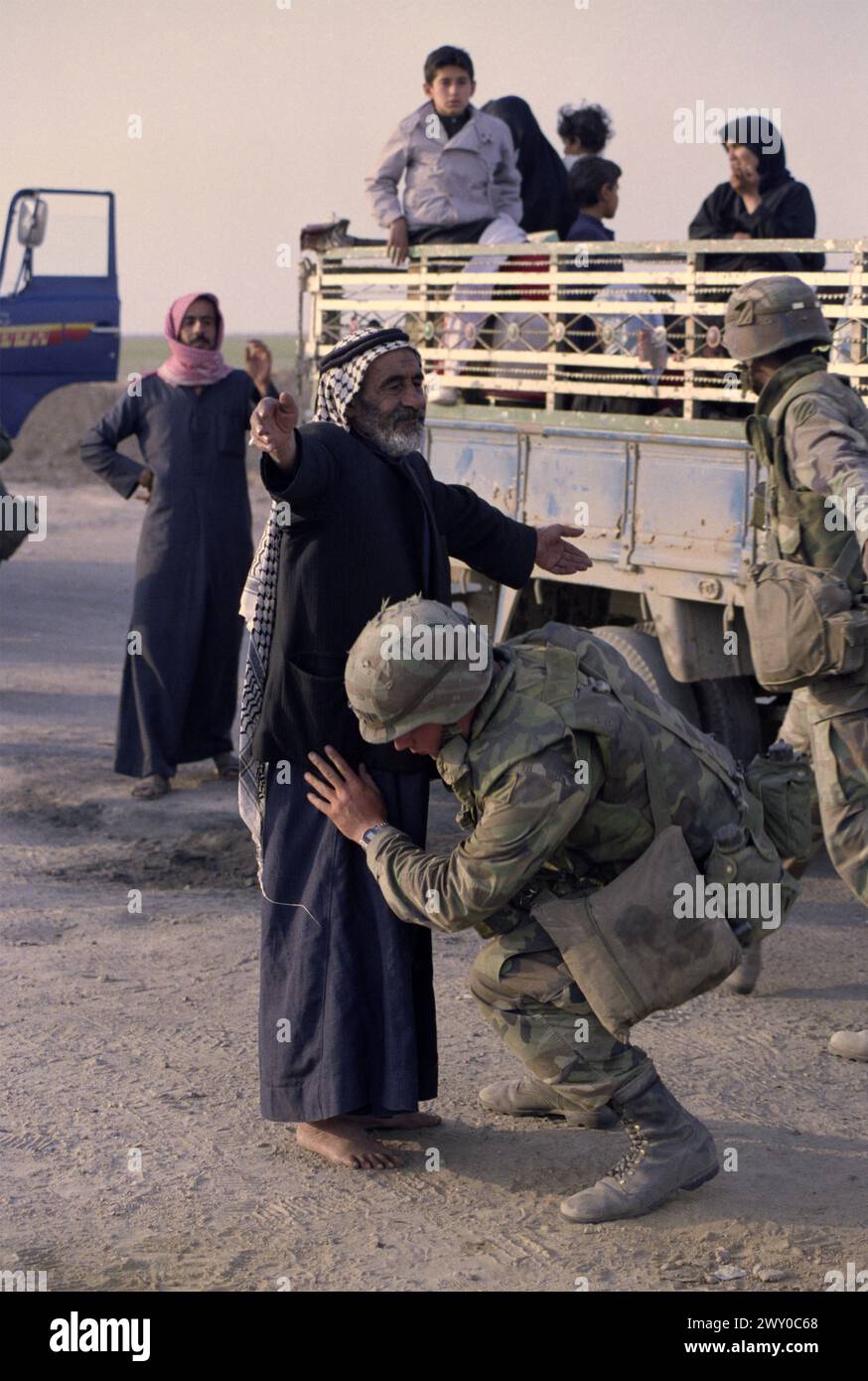 Première Guerre du Golfe : 26 mars 1991 Un soldat de l'armée américaine fouille un vieil homme au dernier poste de contrôle américain, à seulement 8 km au sud de Nasiriyah dans le sud de l'Irak. Banque D'Images