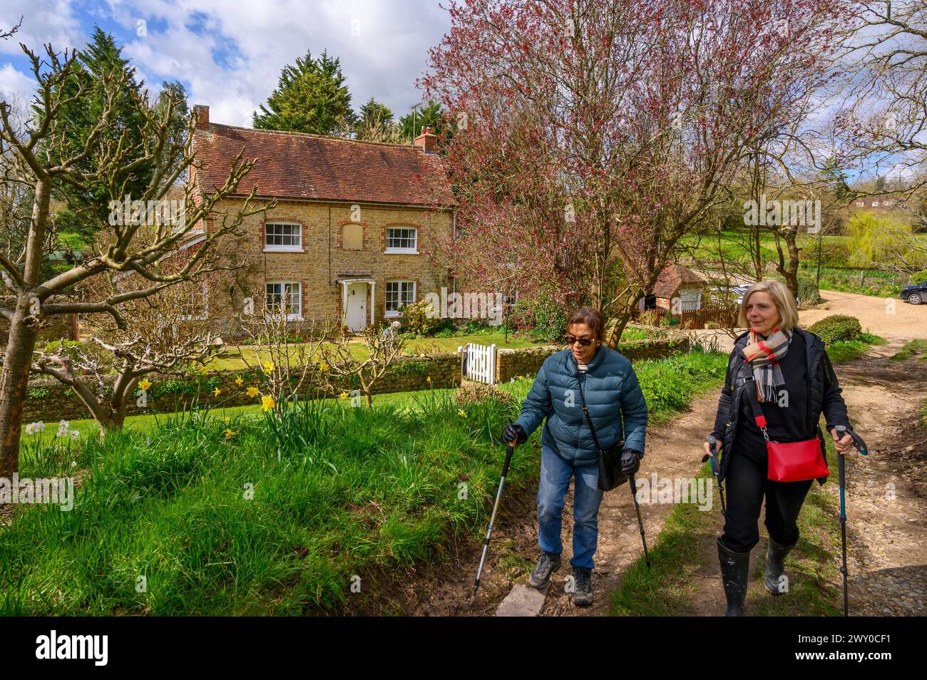 Deux femmes d'âge moyen marchant le long d'une route de gravier devant a Mill House au début du printemps à Nutbourne près de Pulborough dans le West Sussex rural, en Angleterre. Banque D'Images