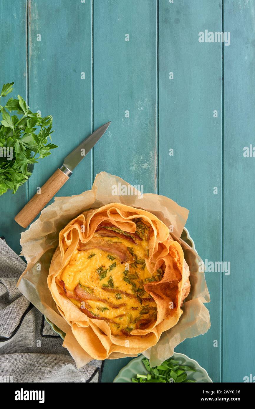 Quiche ou tarte maison avec tranches de bacon et poireaux avec tortilla au lieu de pâte sur planche à découper en bois sur fond rustique vieux en bois. Quiche Banque D'Images