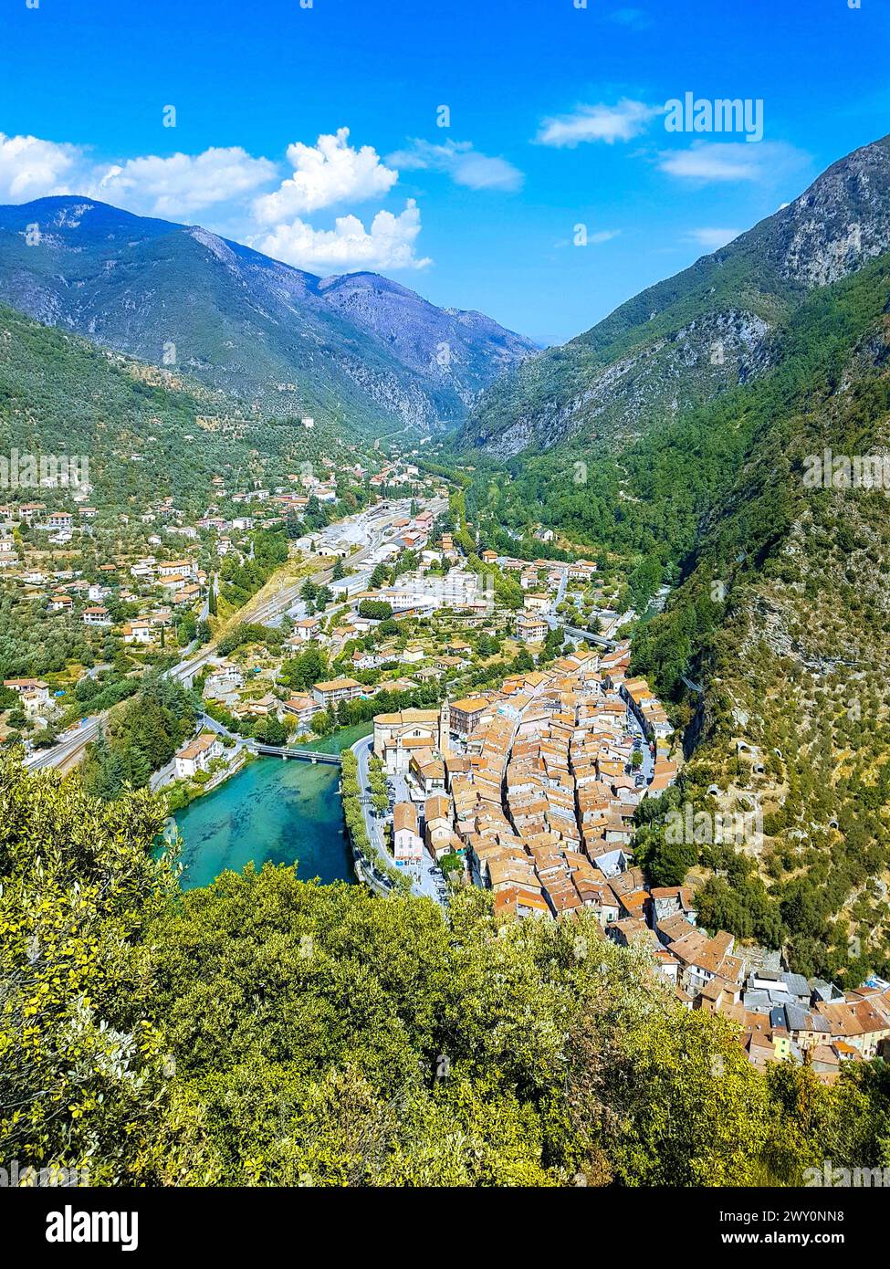 Ville pittoresque entourée d'arbres, avec des montagnes lointaines et une rivière qui coule : Breil-sur-Roya, une commune de France, nichée dans une vallée Banque D'Images