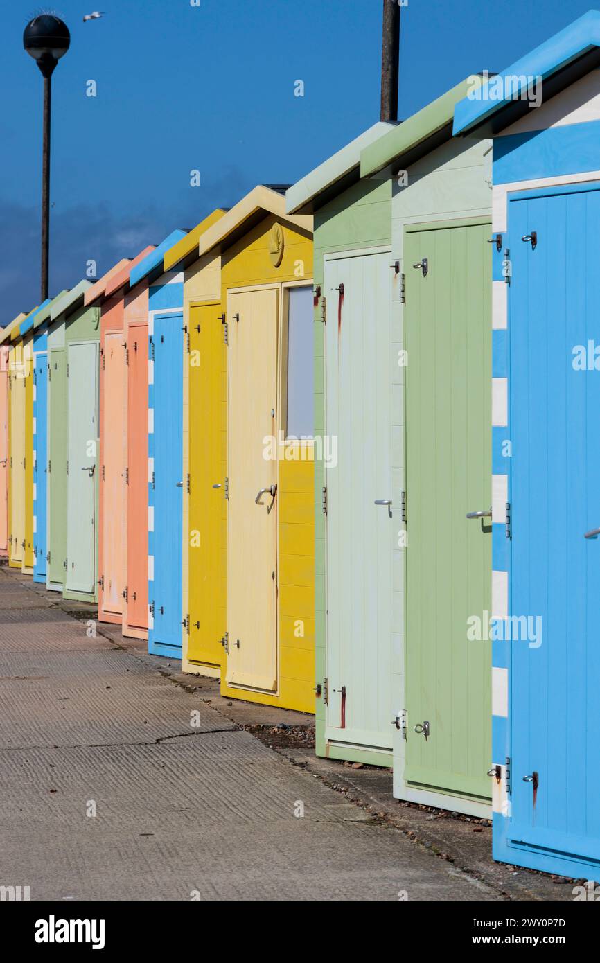 Cabanes de plage à seaford East Sussex UK rangée multicolore de cabanes près de la plage dans des couleurs pastel alternées au printemps par une journée froide et venteuse Banque D'Images