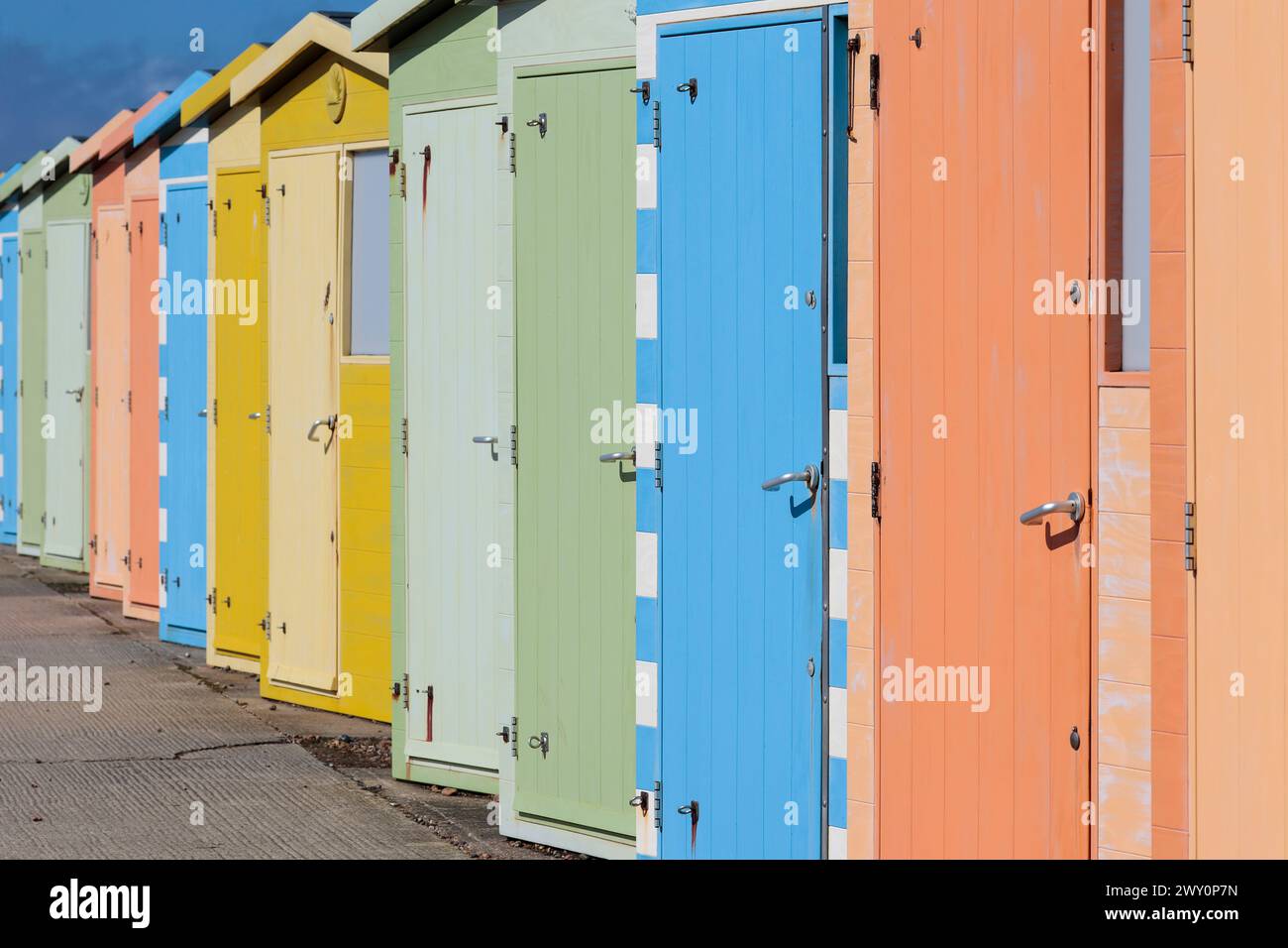 Cabanes de plage à seaford East Sussex UK rangée multicolore de cabanes près de la plage dans des couleurs pastel alternées au printemps par une journée froide et venteuse Banque D'Images