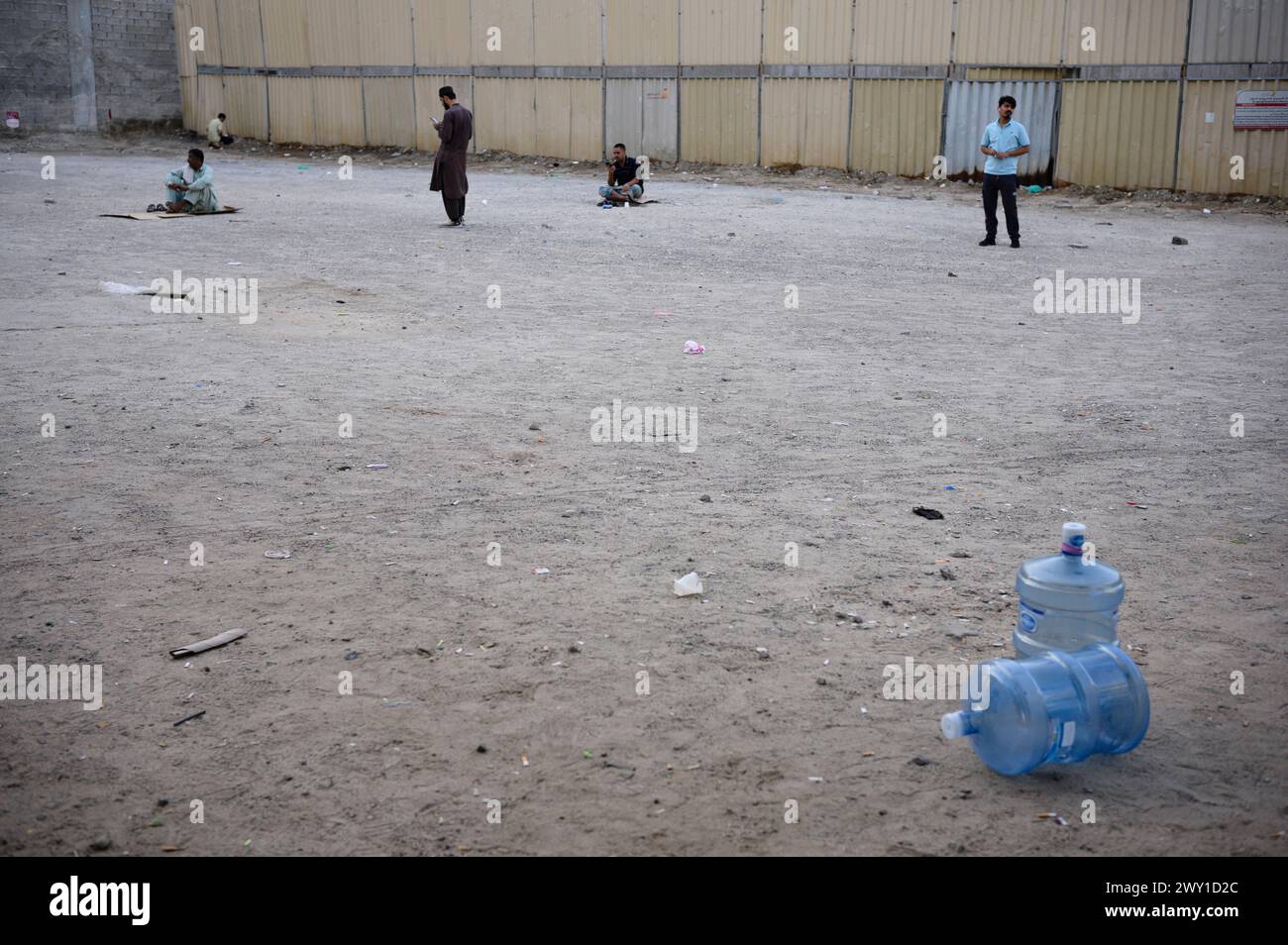 Männer stehen oder sitzen auf einem unbebauten Platz - Dubai - Vereinigte Arabische Emirate, 09.01.2024 *** hommes debout ou assis sur un terrain vacant Dubaï Émirats Arabes Unis, 09 01 2024 Banque D'Images