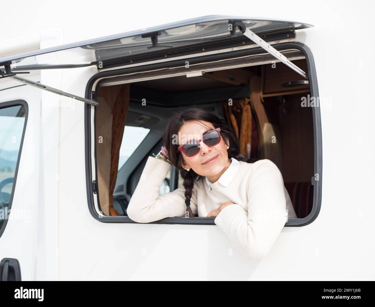 Femme brune latine appuyée sur la fenêtre du camping-car Banque D'Images