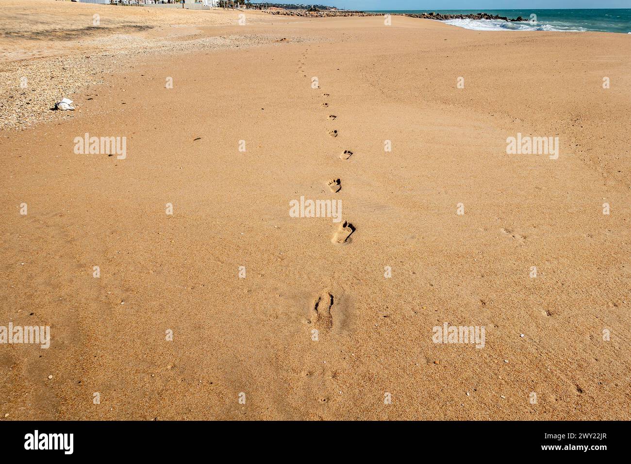 Sentier de pas isolé dans la distance sur cette plage de sable de Quarteira, Portugal. Banque D'Images