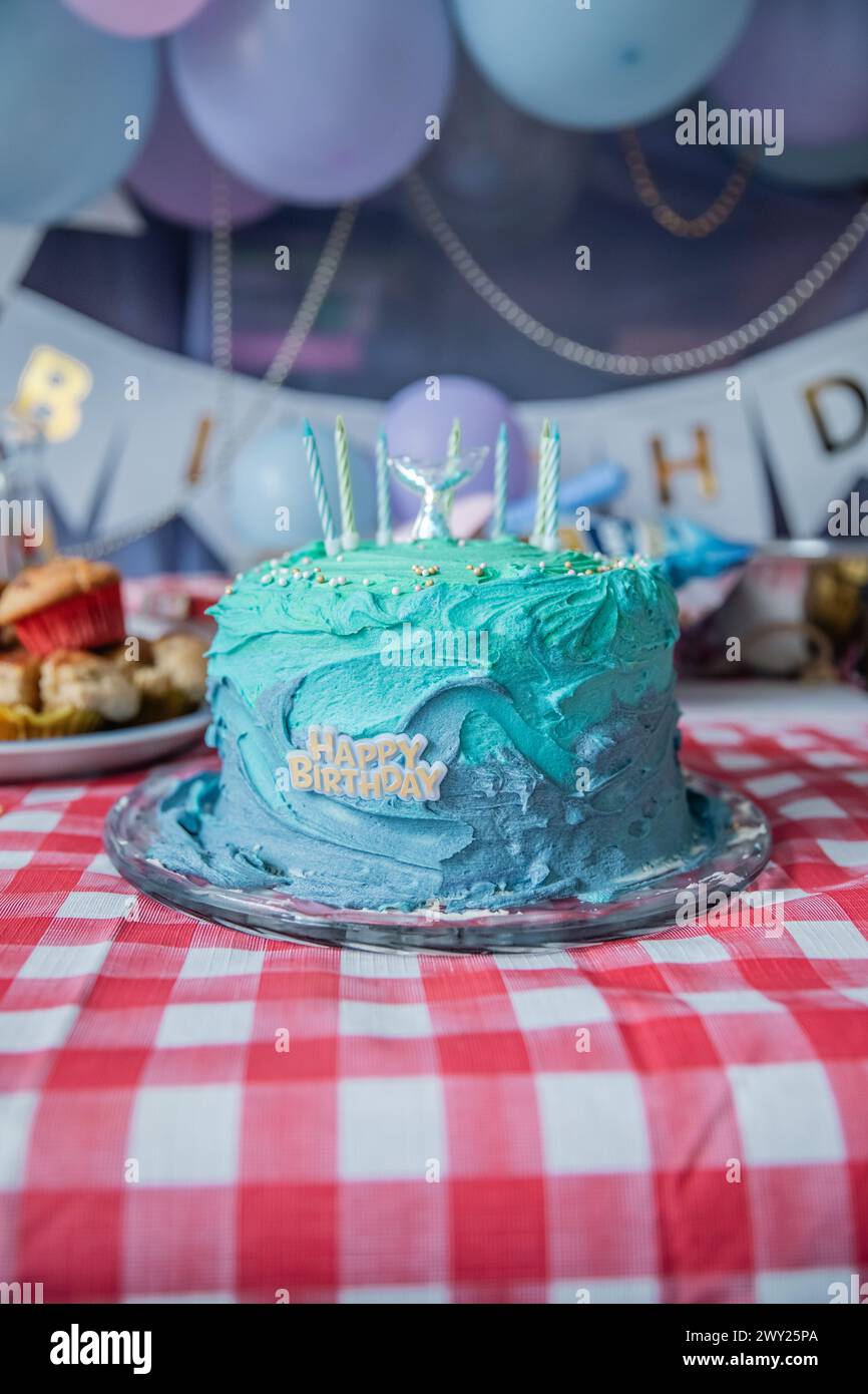 Un gâteau d'anniversaire bleu et sarcelle pour filles à thème sirène avec des bougies, des ballons, des friandises sucrées, du glaçage comestible, des muffins, cupcakes et plus encore ! Banque D'Images