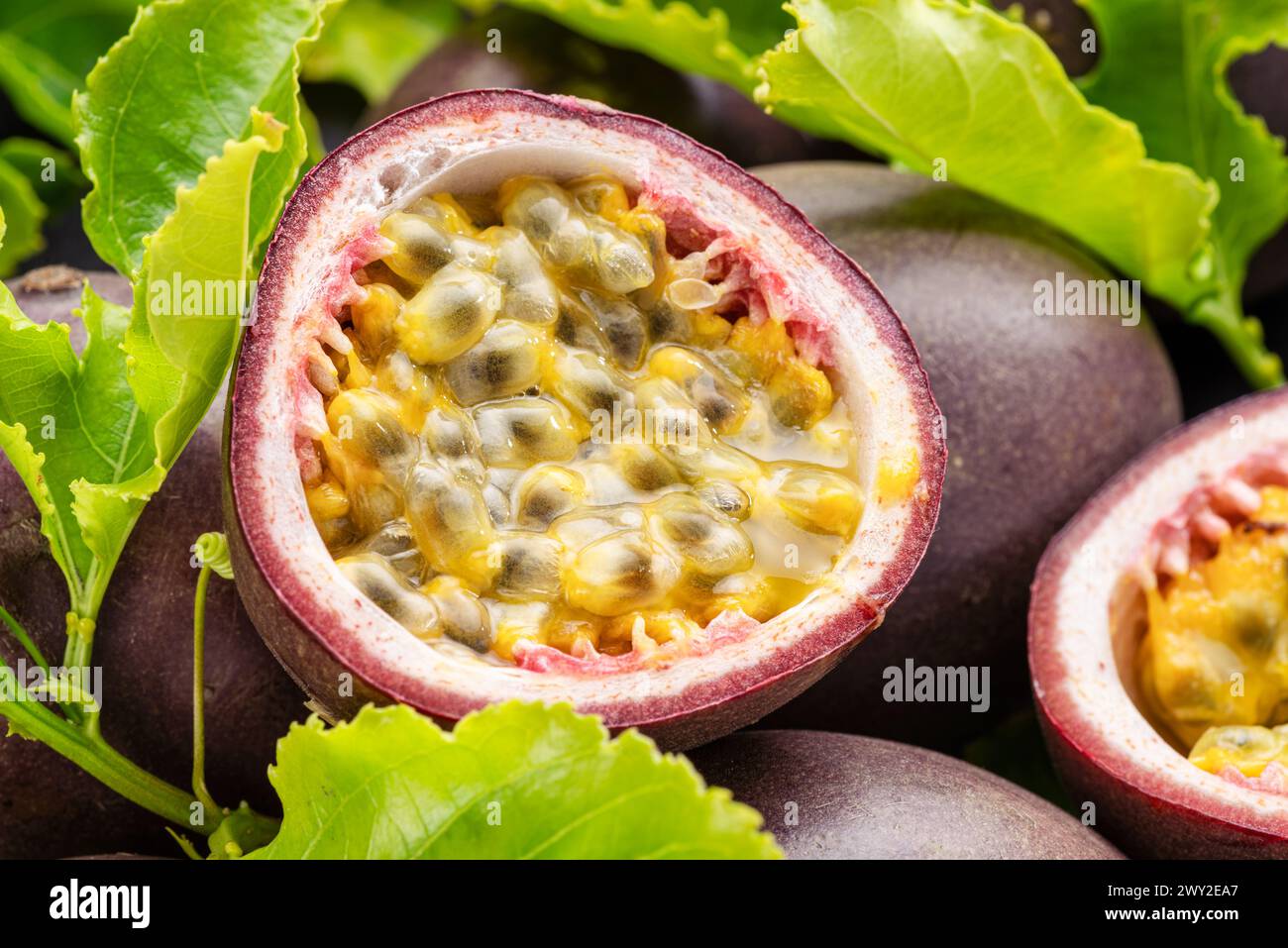 Fruits de la passion mûrs avec des graines de fruits de la passion et des feuilles de fruits de la passion sur une table en pierre grise. Joli fond de fruits exotiques pour vos projets. Banque D'Images