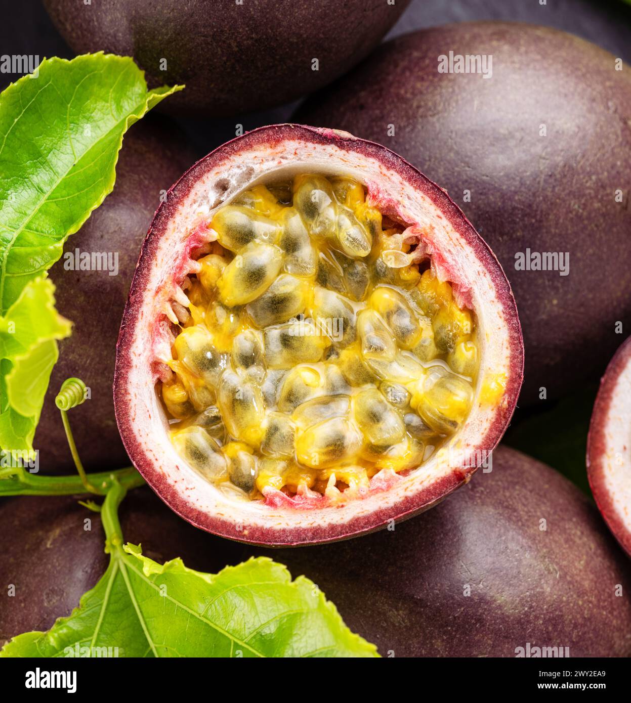 Fruits de la passion mûrs avec des graines de fruits de la passion et des feuilles de fruits de la passion sur une table en pierre grise. Joli fond de fruits exotiques pour vos projets. Banque D'Images