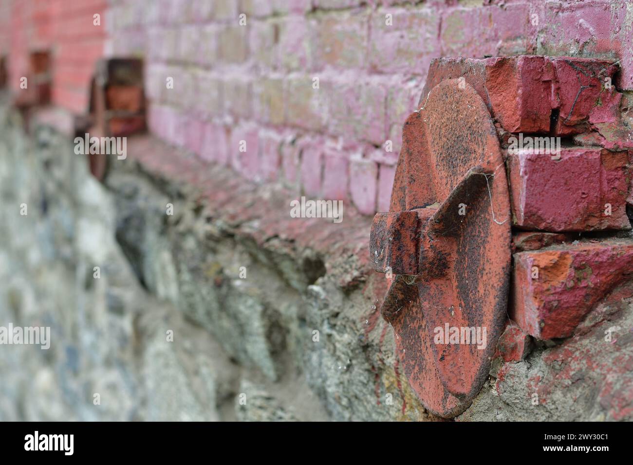 Dispositif de retenue de mur de briques de style ancien. Vieux mur de briques renforcé avec des plaques métalliques rondes. Banque D'Images