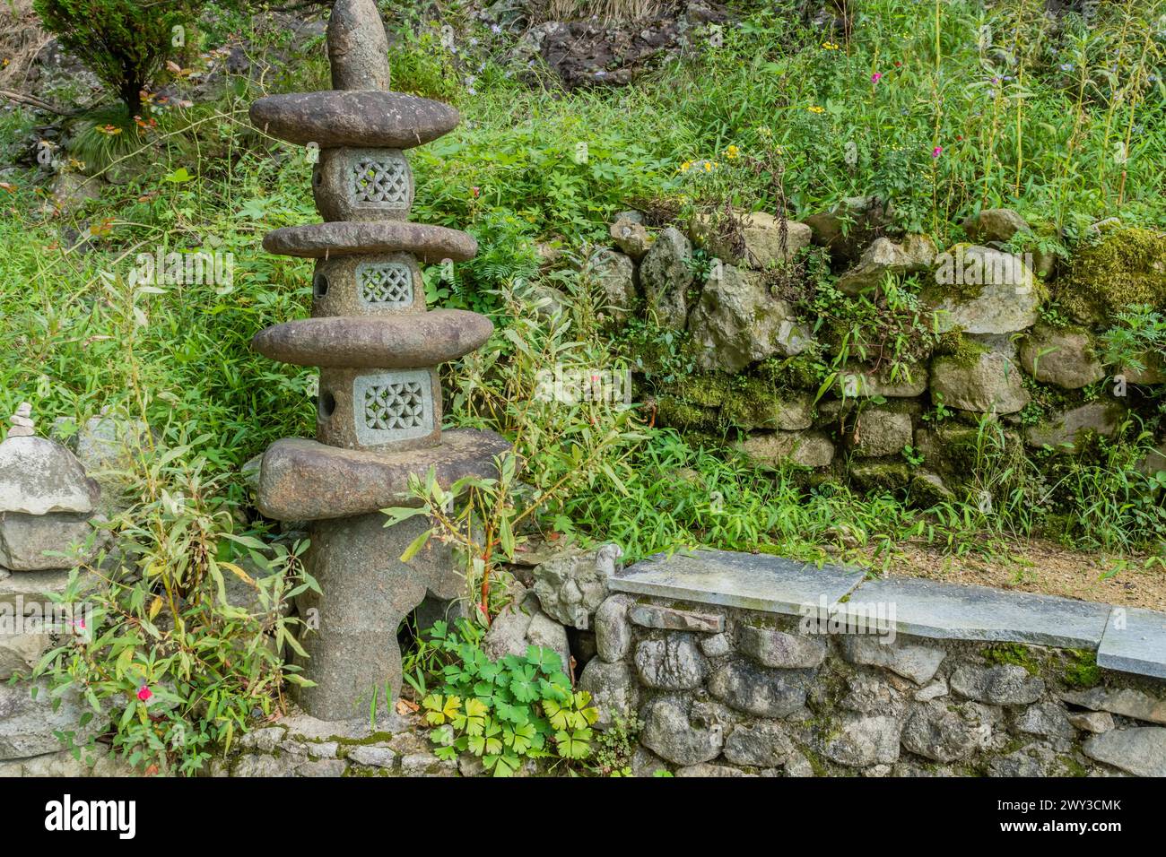 Pagode de pierre contre feuillage vert à côté d'un mur de pierre en Corée du Sud Banque D'Images