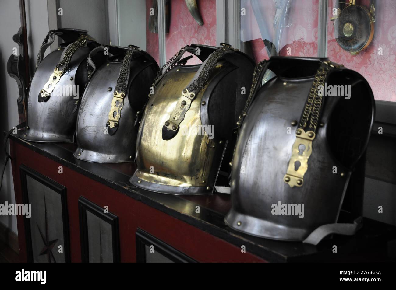 Château de Langenburg, rangée de casques en métal brillant avec des chaînes sur une surface rouge, Château de Langenburg, Langenburg, Bade-Wuertemberg, Allemagne Banque D'Images