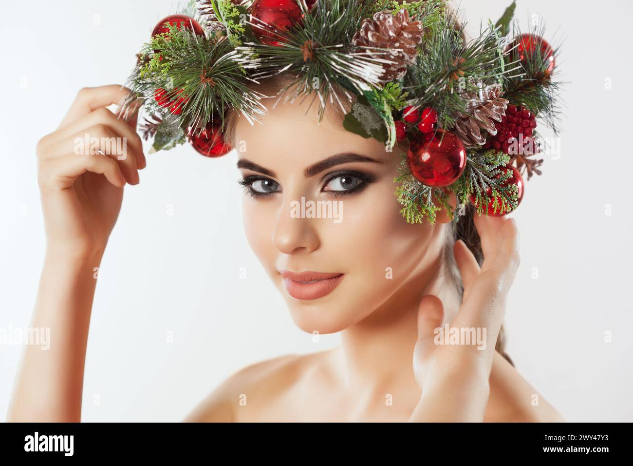 Une jolie jeune femme, sur sa tête une belle couronne d'épicéa avec des cônes et des boules. Concept du nouvel an. Banque D'Images
