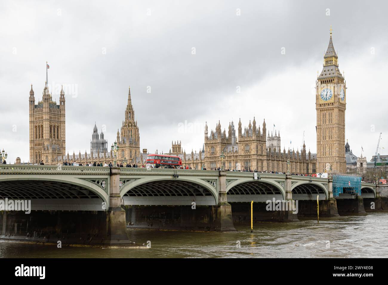 Un bus rouge londonien traversant le pont Westminster. Derrière, Big Ben et les chambres du Parlement, symbole emblématique de la démocratie et du patrimoine britanniques. Banque D'Images