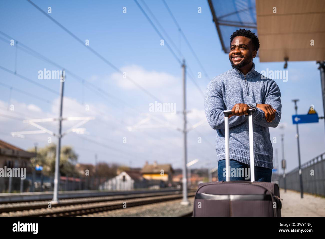 Homme heureux avec valise debout sur la gare. Banque D'Images
