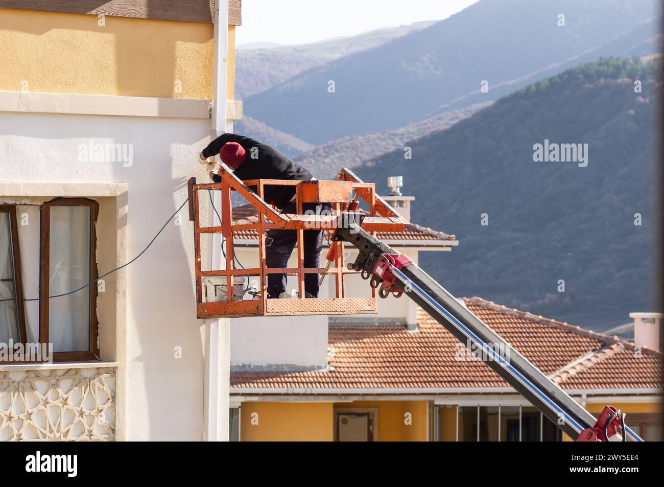 Travailleur sans casque réparant la conduite d'eau sur la grue, vissez avec une perceuse Banque D'Images