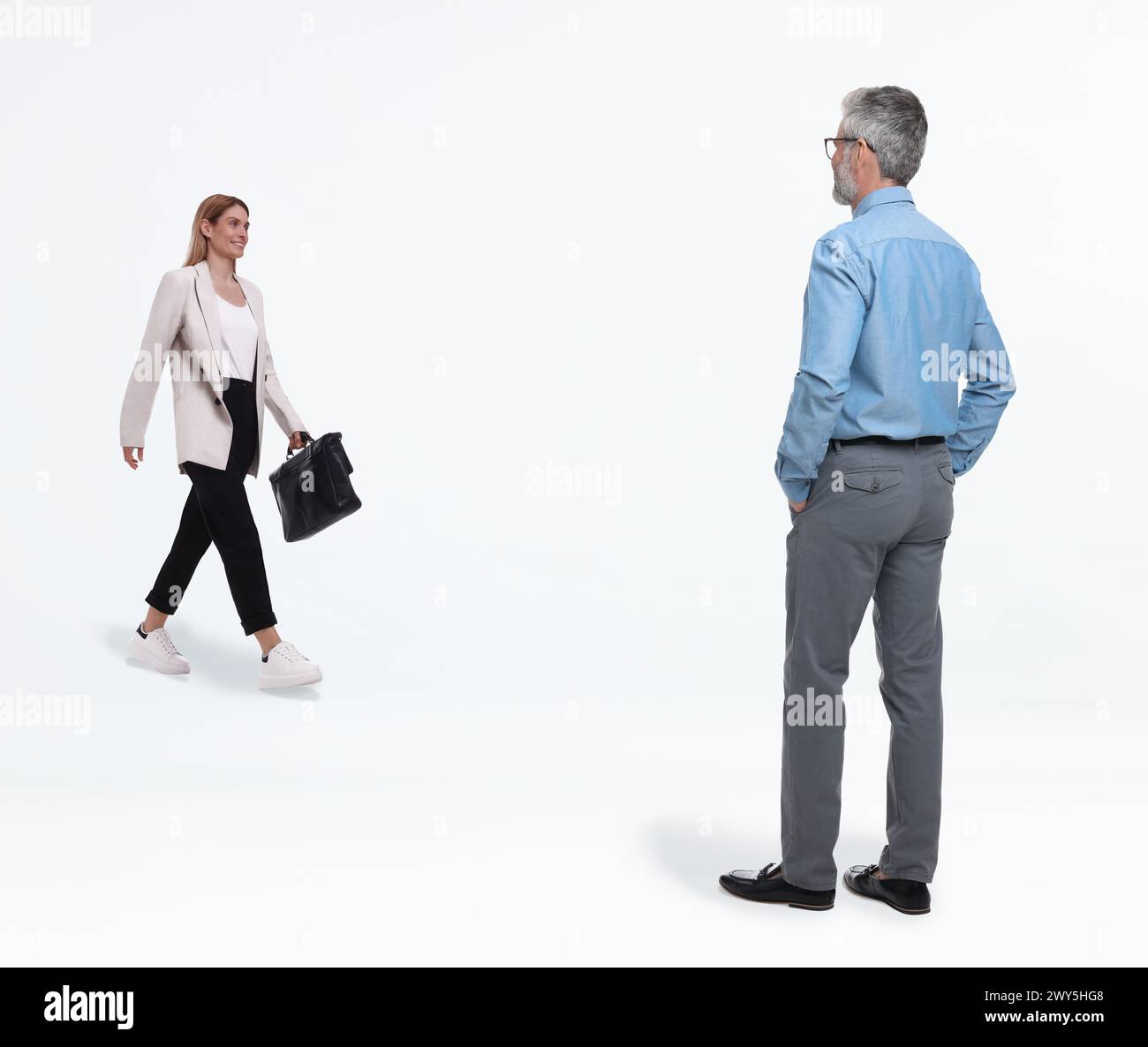 Petite femme marchant vers l'homme géant sur fond blanc Banque D'Images