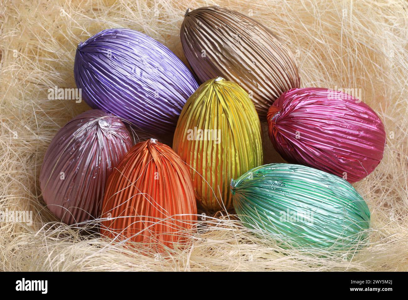 Oeufs colorés en chocolat de Pâques dans un nid de paille. Banque D'Images